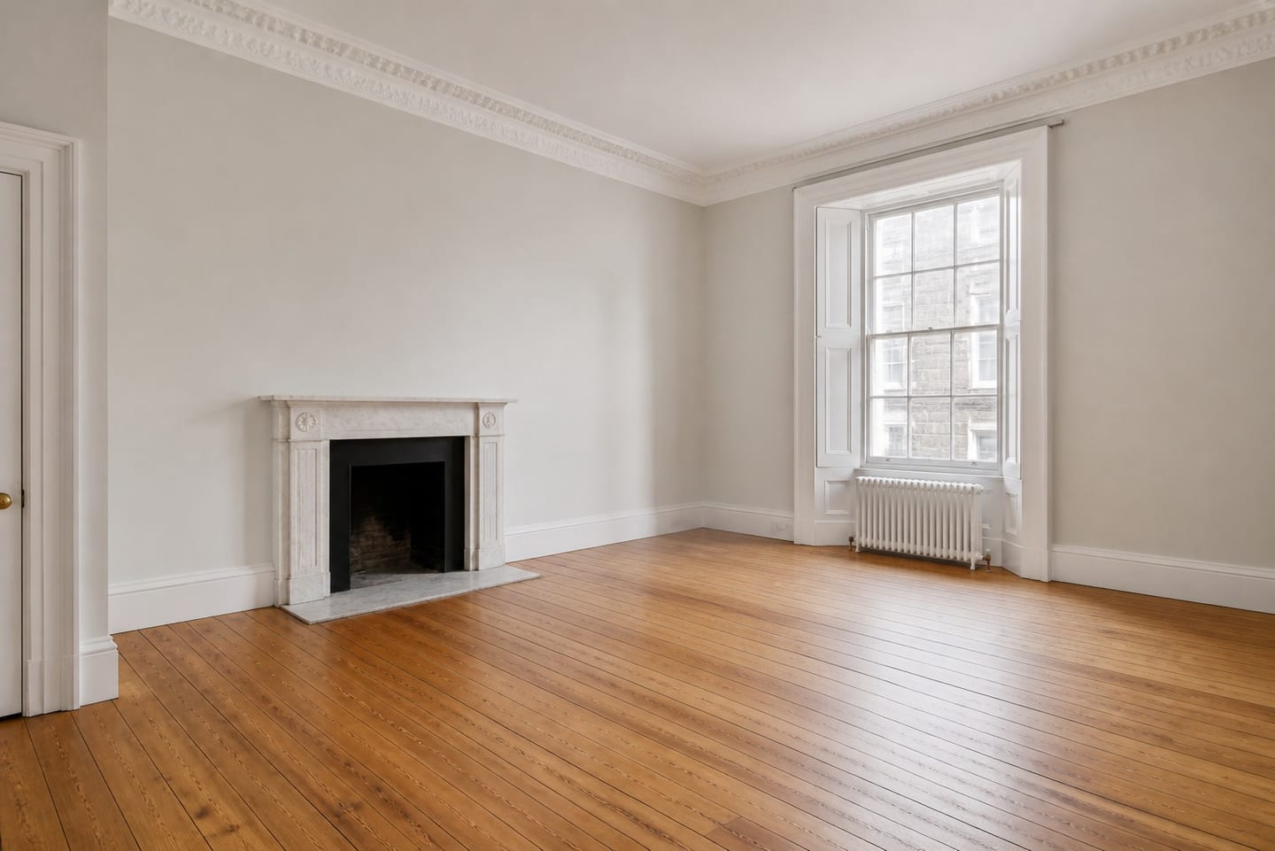 Empty Edinburgh New Town drawing room with a marble chimneypiece, deep cornice and shuttered sash window, shown before and after virtual staging with a dark sofa, swivel chair and marble coffee table — before