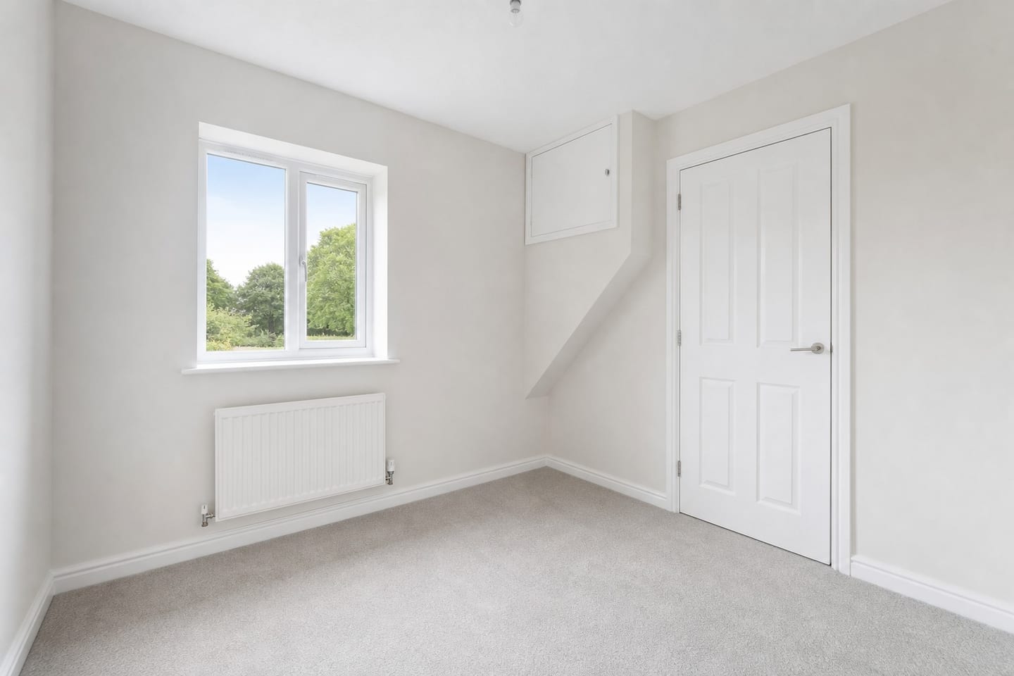 Empty small bedroom with a casement window, radiator and an over-stair bulkhead cupboard, shown before and after virtual staging with a single rattan bed, basket storage unit, jute rug and a blue beanbag — before