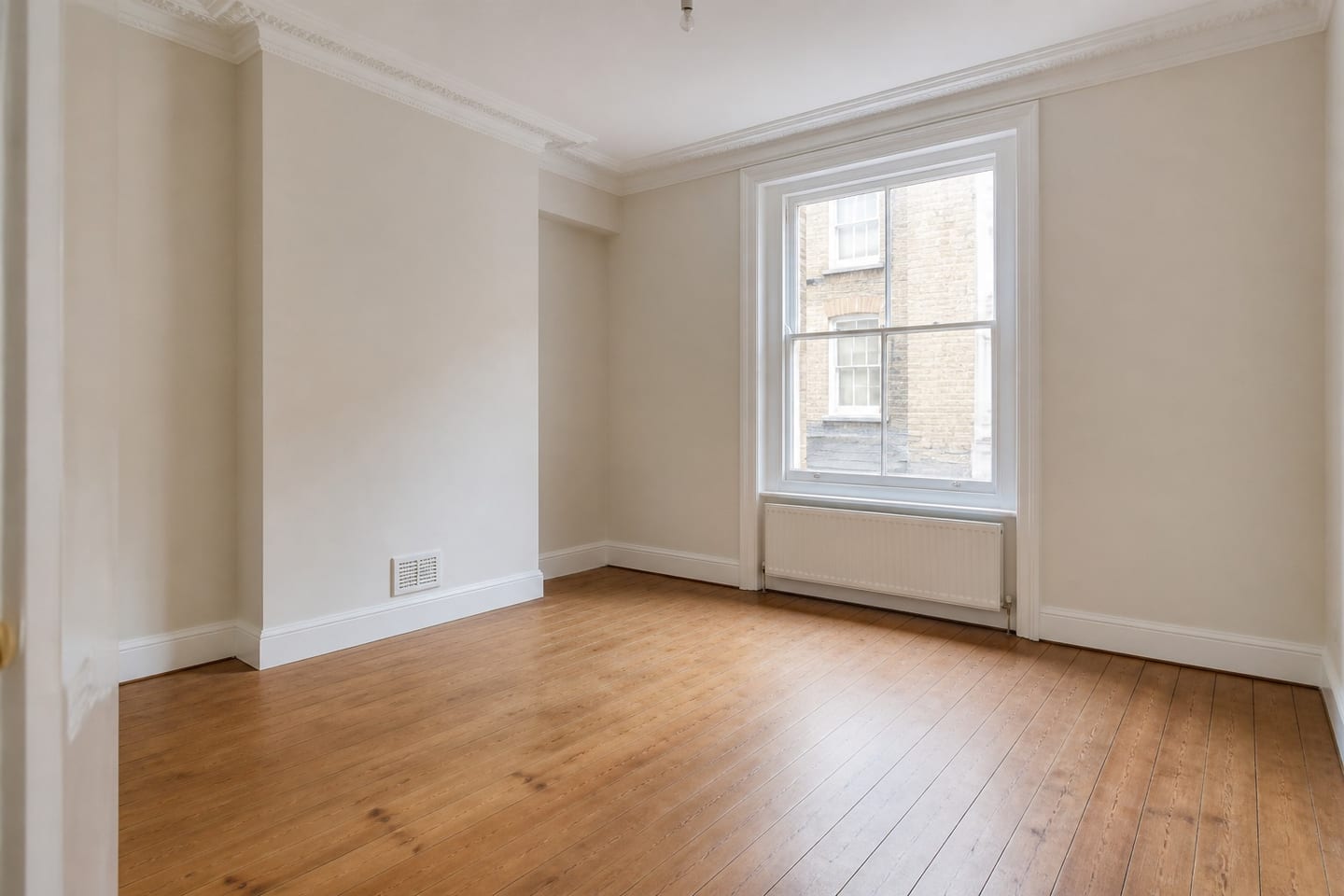 Empty Victorian reception room with cornicing, a chimney-breast alcove and a sash window, shown before and after virtual staging with a sofa, armchairs, a patterned rug and framed art — before
