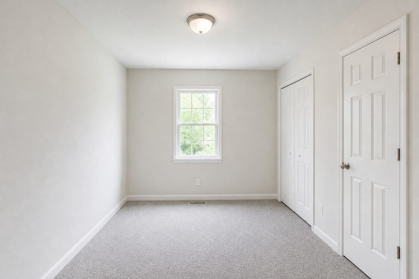 Empty small secondary bedroom in a tract house with one double-hung window, a floor register beneath it, a reach-in closet and hallway door on the same wall, and grey carpet, shown before and after virtual staging with a bed, nightstand, lamp and rug — before