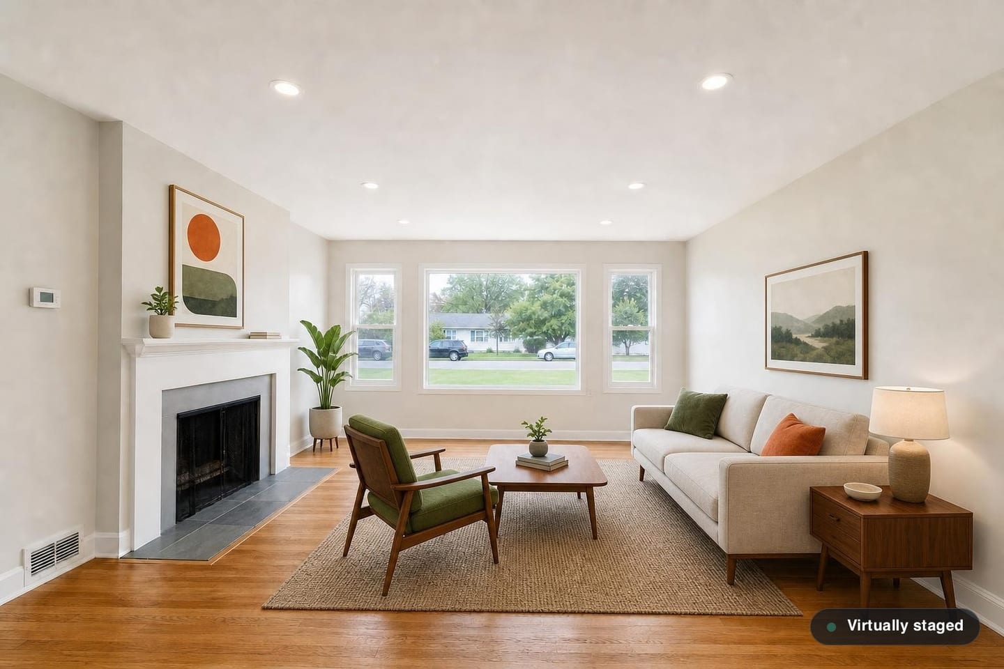 The same empty ranch front living room, shown before and after virtual staging in a Mid-Century scheme with a walnut coffee table on tapered legs, a walnut credenza, a green-cushioned lounge chair and a rust accent pillow — after